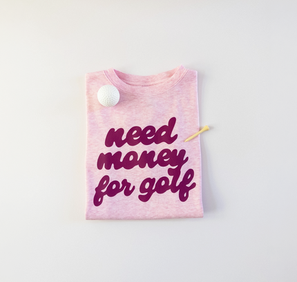 Pink t-shirt with 'need money for golf' text on a light gray background
