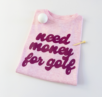 Pink t-shirt with 'need money for golf' text on a white background