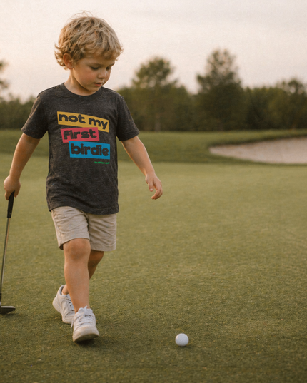 Child on a golf course with a golf club and ball