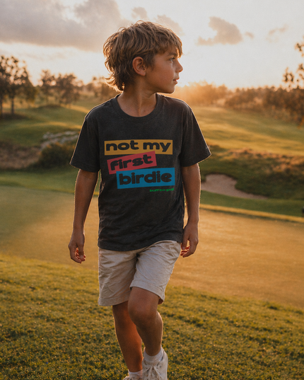 Child wearing a t-shirt with text on a golf course at sunset