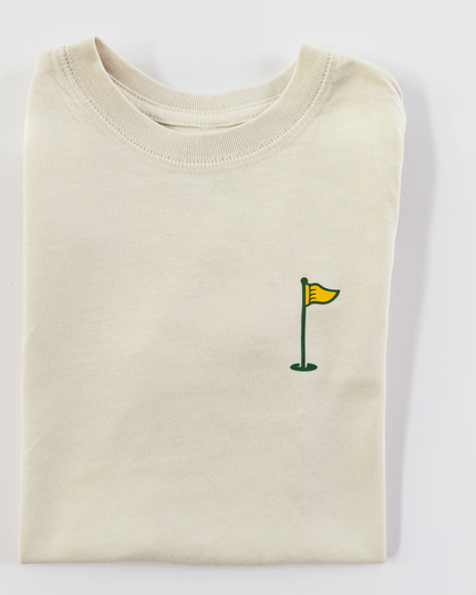 Folded cream-colored sweatshirt with a small green flag design on a light gray background