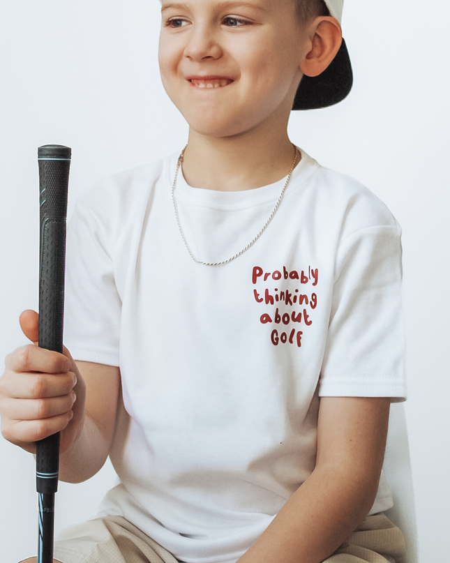 Child wearing a white t-shirt with text and holding a golf club against a white background