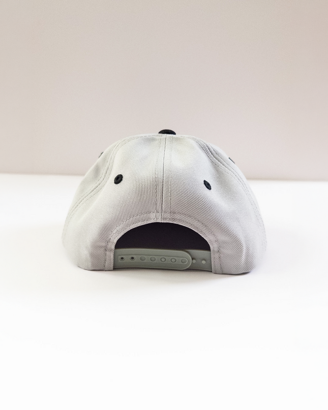 grey cap with black buttons on a light pink background