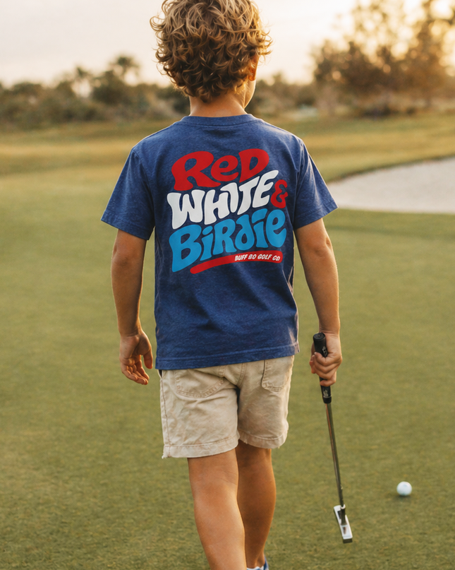 Child on a golf course wearing a 'Red White & Blue' t-shirt