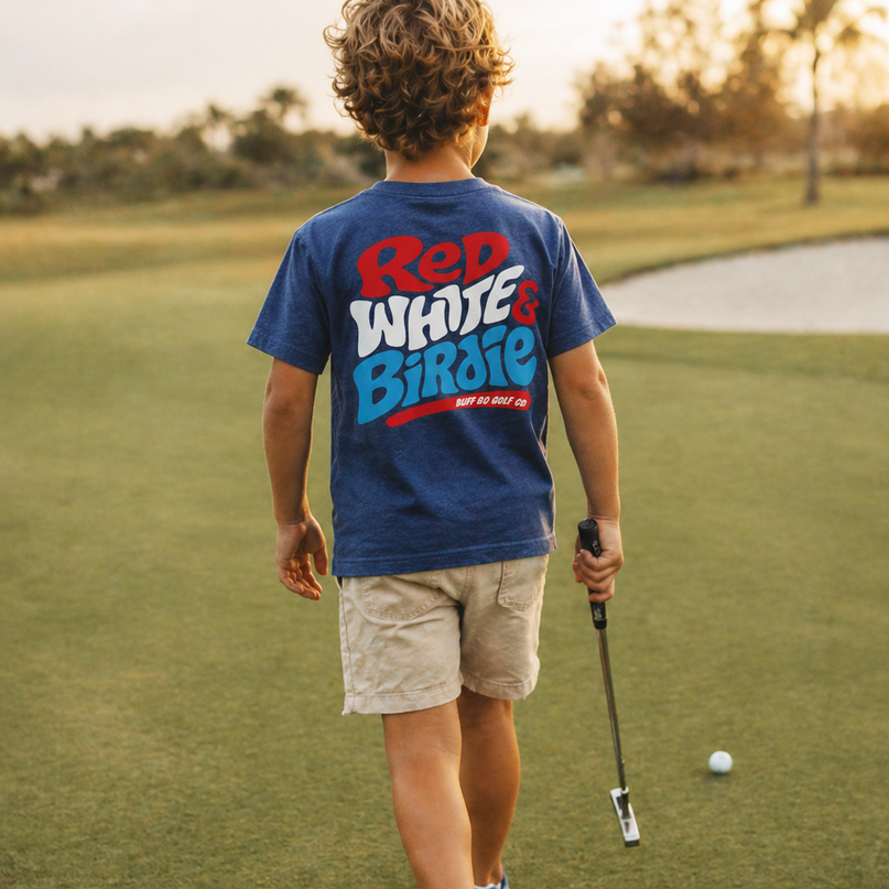 Child on a golf course wearing a 'Red White & Blue' t-shirt