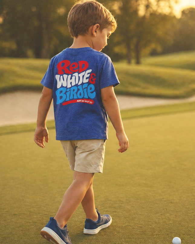 Child walking on a golf course wearing a blue shirt with red and white text.