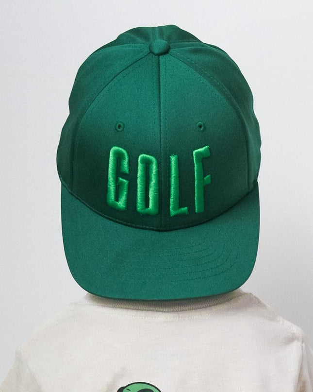 Person wearing a green 'GOLF' cap and a white t-shirt with a skeleton design on a plain background