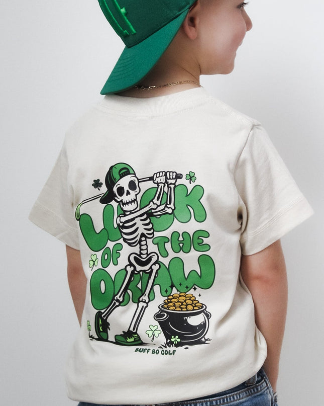 Child wearing a white t-shirt with a graphic design and a green cap on a plain background