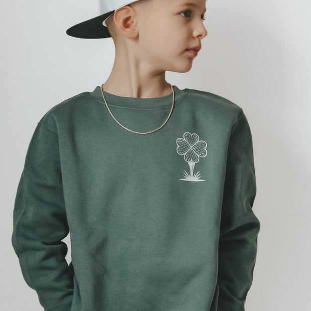 Child wearing a green sweatshirt with a four-leaf clover design on a plain background