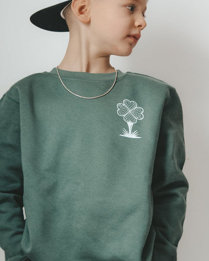 Child wearing a green sweatshirt with a white graphic design on a plain background