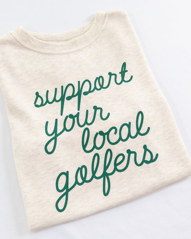 Buff Bo Outfitters' 'Support Your Local Golfers' kids' t-shirt in soft cream. A stylish and comfortable tee celebrating young golfers and the love of the game.