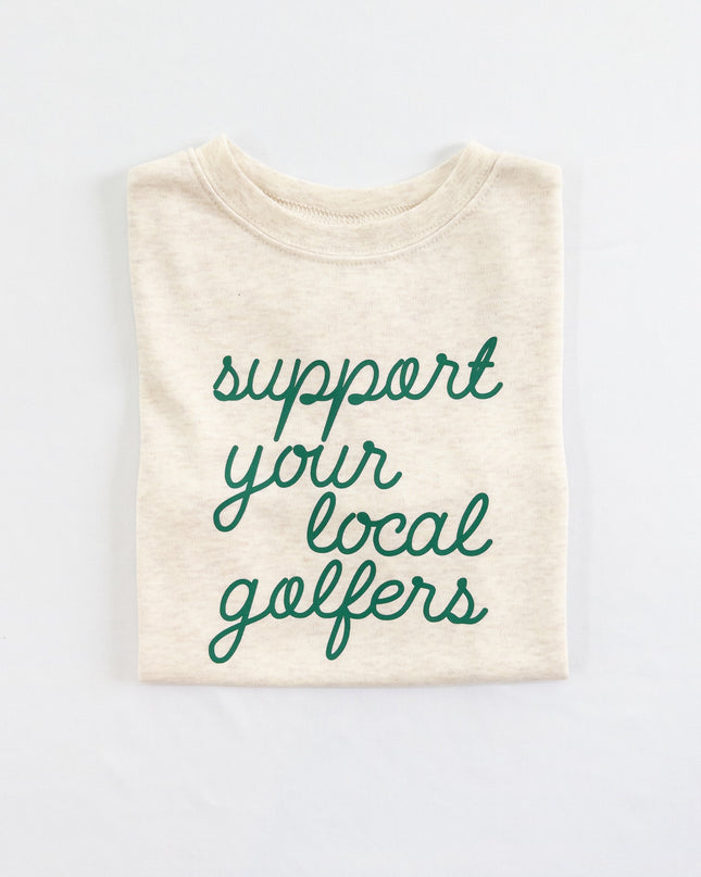 Buff Bo Outfitters' 'Support Your Local Golfers' kids' t-shirt in soft cream. A stylish and comfortable tee celebrating young golfers and the love of the game.