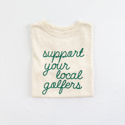 Buff Bo Outfitters' 'Support Your Local Golfers' kids' t-shirt in soft cream. A stylish and comfortable tee celebrating young golfers and the love of the game.