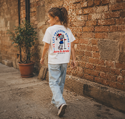 Child walking on a street wearing a t-shirt with text and graphics.