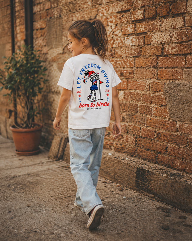 Child walking on a street wearing a t-shirt with text and graphics.