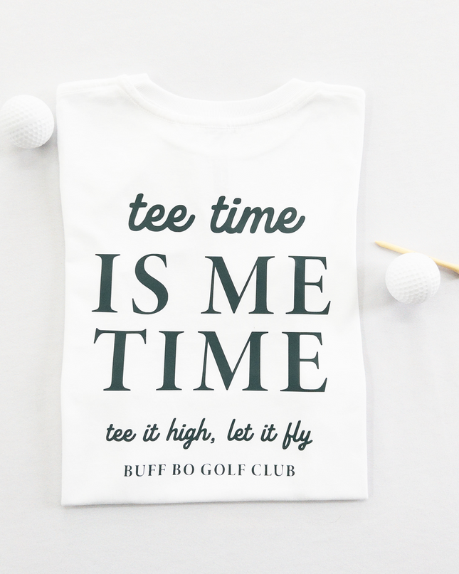 White kids golf t-shirt featuring dark green text reading 'tee time is me time' with additional script text 'tee it high, let it fly' and 'Buff Bo Golf Club,' styled flat with golf balls and a wooden tee, fun and motivational golf apparel for kids.