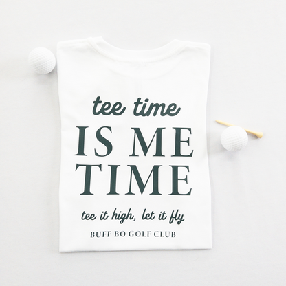 White kids golf t-shirt featuring dark green text reading 'tee time is me time' with additional script text 'tee it high, let it fly' and 'Buff Bo Golf Club,' styled flat with golf balls and a wooden tee, fun and motivational golf apparel for kids.