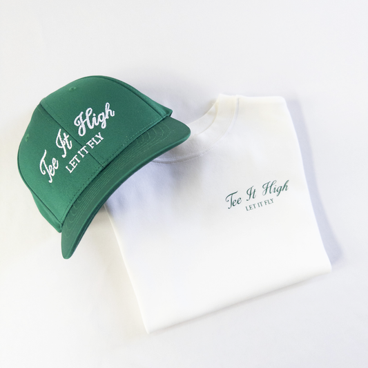 "Green embroidered 'Tee It High, Let It Fly' golf cap and white t-shirt neatly folded, featuring the same slogan, from Buff Bo Outfitters. Stylish and high-quality golf apparel for kids."