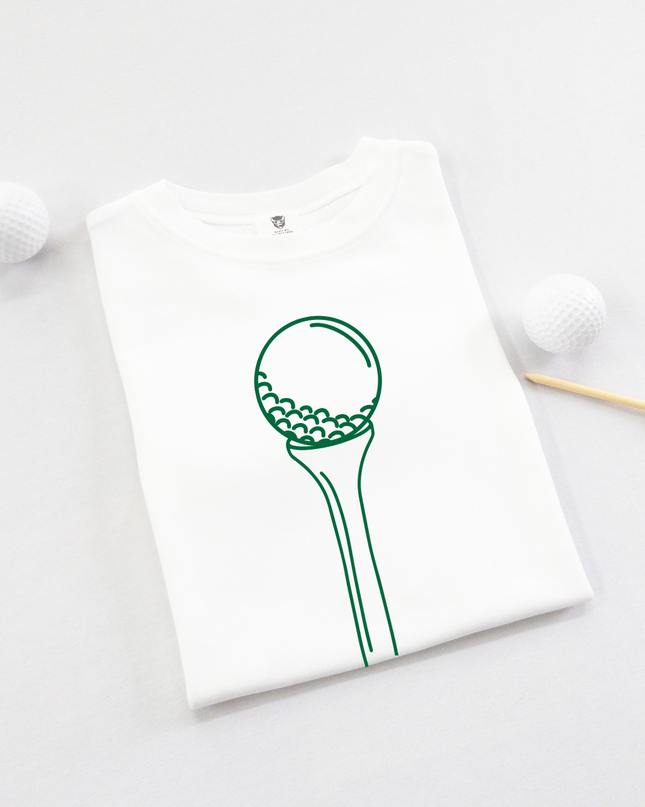 White t-shirt with green graphic of a golf ball on a tee on a light gray background