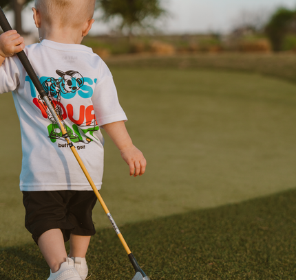 Child holding a golf club on a golf course