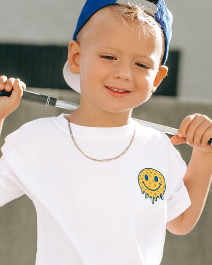 Child wearing a white t-shirt with a smiley face design, holding a baseball bat, against a neutral background.